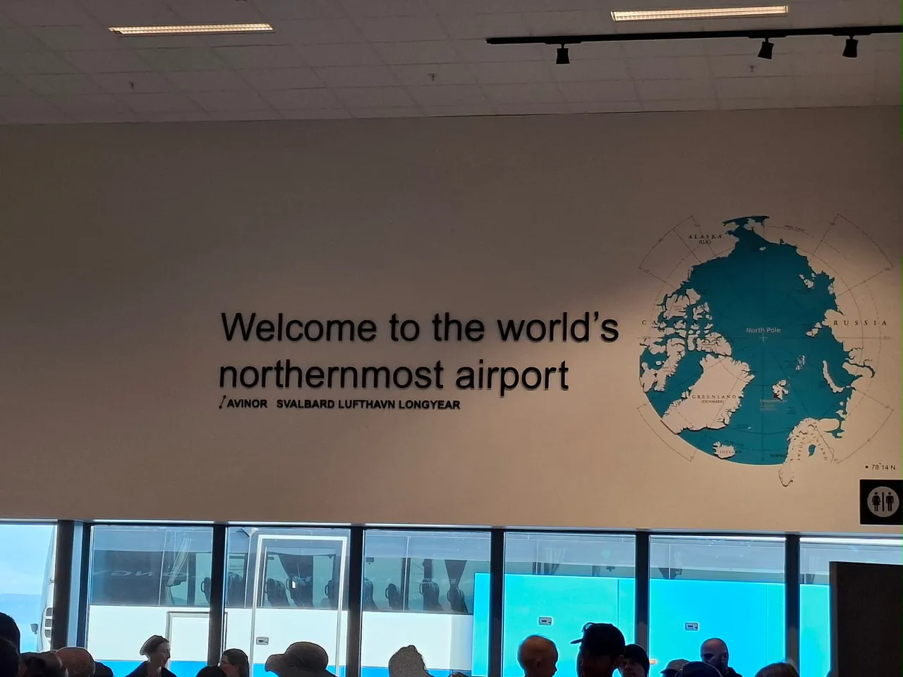 The arrivals hall at Svalbard Airport, with a wall map of the Arctic and the words 'Welcome to the world's northernmost airport'