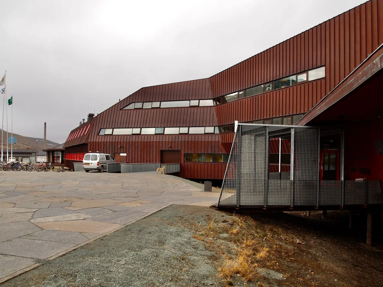 The red, angular facade of Svalbard Museum and the research park, with a paved square in front