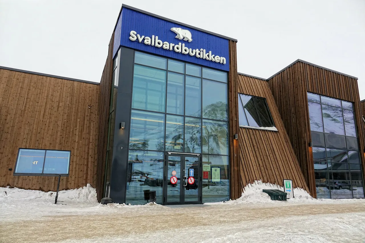 The glass entrance of Svalbardbutikken, with its name and a polar bear logo above the door, in a wooden building on a snowy street